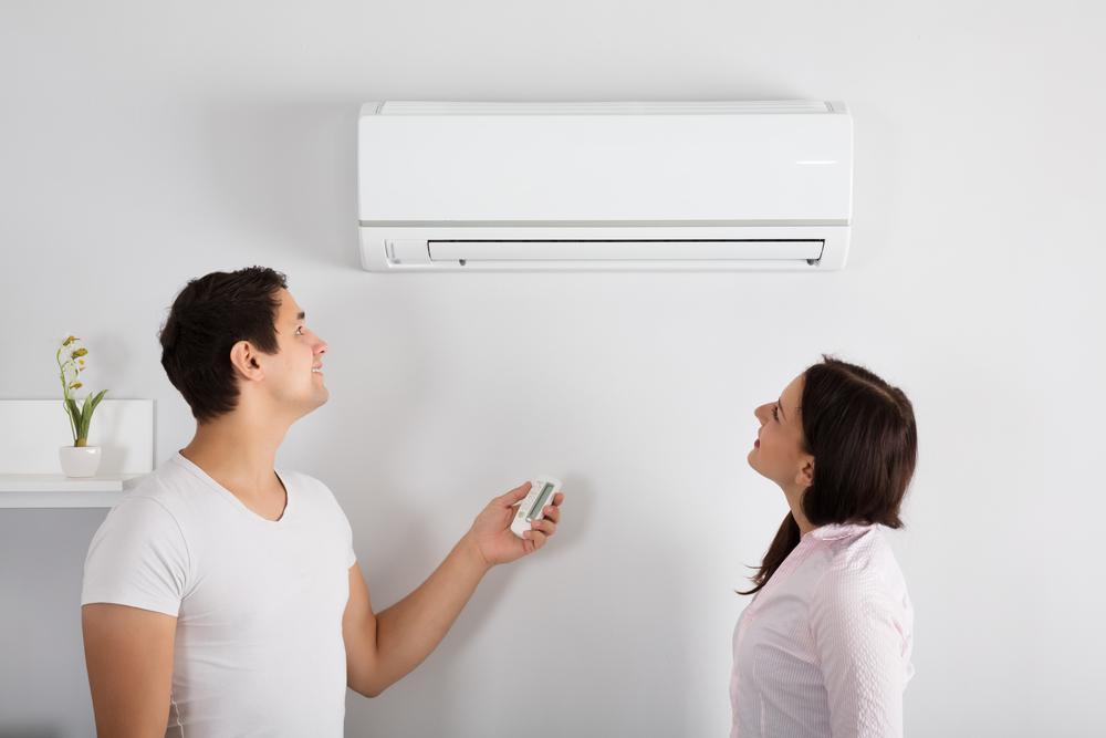 Man and woman using remote to turn on heat pump in their New Orleans home.